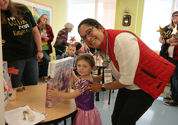 little girl holding toy and smiling with an adult 
